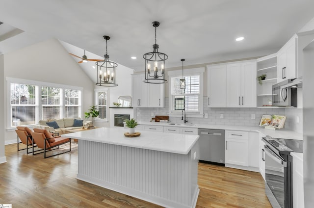 kitchen with hanging light fixtures, stainless steel appliances, white cabinets, and a kitchen island