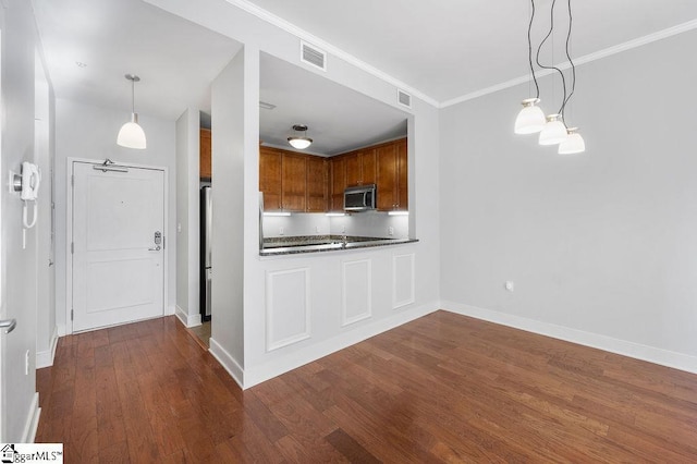 kitchen with hanging light fixtures, crown molding, and dark wood-type flooring