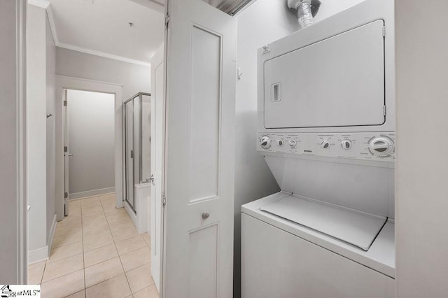 laundry area with crown molding, stacked washer and clothes dryer, and light tile patterned flooring