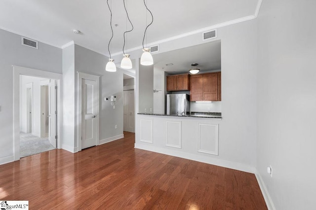 kitchen featuring ornamental molding, stainless steel fridge, decorative light fixtures, and hardwood / wood-style floors