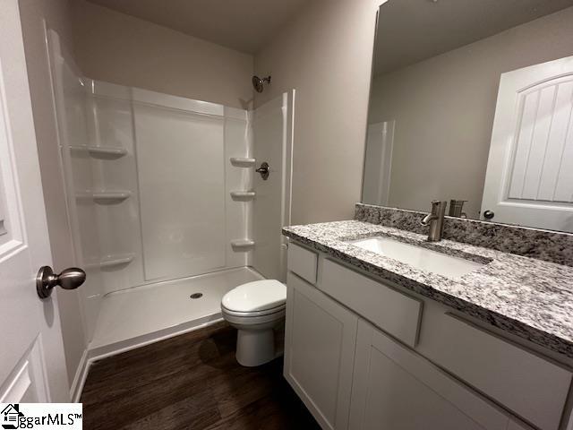 bathroom featuring vanity, hardwood / wood-style flooring, toilet, and a shower