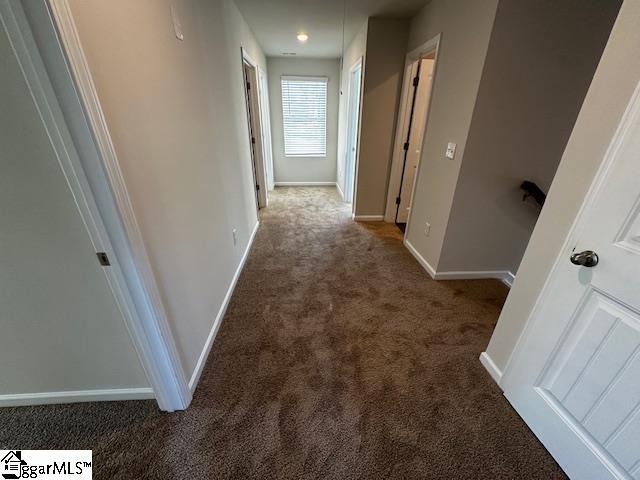 hall featuring dark colored carpet