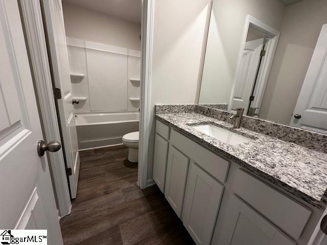 full bathroom with hardwood / wood-style flooring, vanity,  shower combination, and toilet