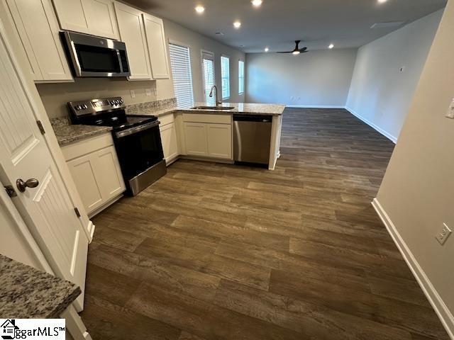 kitchen featuring sink, white cabinetry, dark hardwood / wood-style floors, kitchen peninsula, and stainless steel appliances