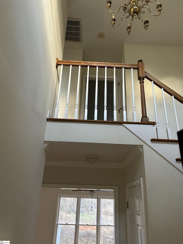 staircase featuring a notable chandelier and ornamental molding