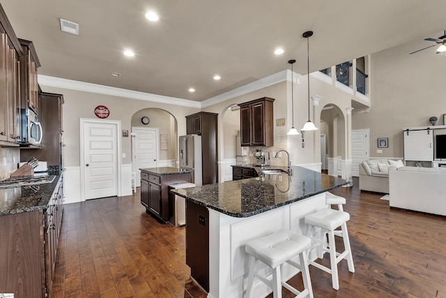 kitchen with appliances with stainless steel finishes, sink, hanging light fixtures, and dark stone countertops