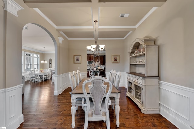 dining area with a chandelier, coffered ceiling, ornamental molding, dark hardwood / wood-style flooring, and beamed ceiling