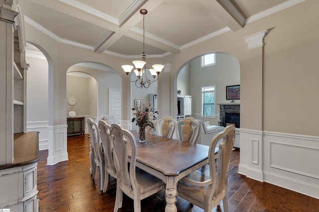 dining space featuring beamed ceiling, coffered ceiling, dark hardwood / wood-style floors, and a fireplace