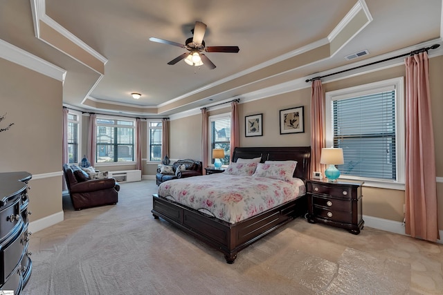 bedroom featuring crown molding, ceiling fan, a tray ceiling, and light carpet