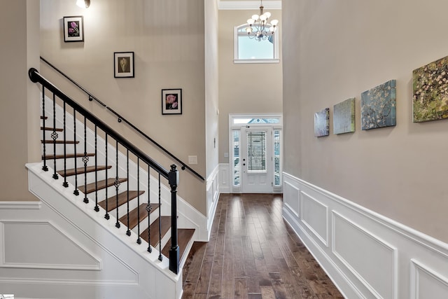 foyer with an inviting chandelier, a towering ceiling, and dark hardwood / wood-style flooring