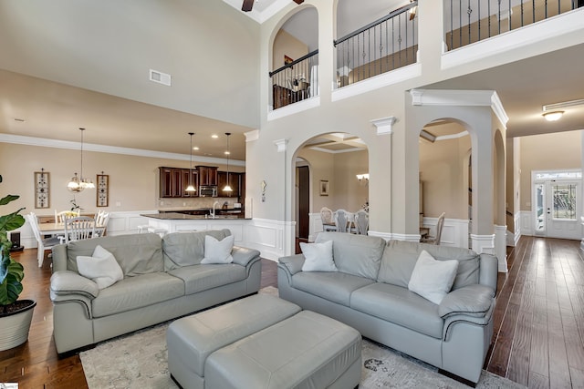 living room featuring a notable chandelier, crown molding, sink, and hardwood / wood-style flooring