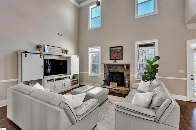 living room featuring ornamental molding, wood-type flooring, a fireplace, and a towering ceiling