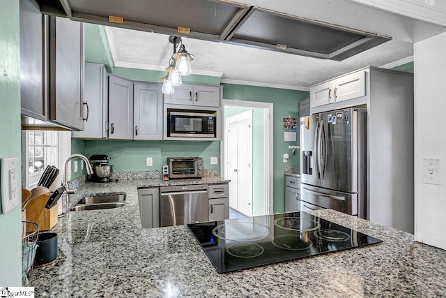 kitchen with sink, light stone counters, hanging light fixtures, ornamental molding, and stainless steel appliances