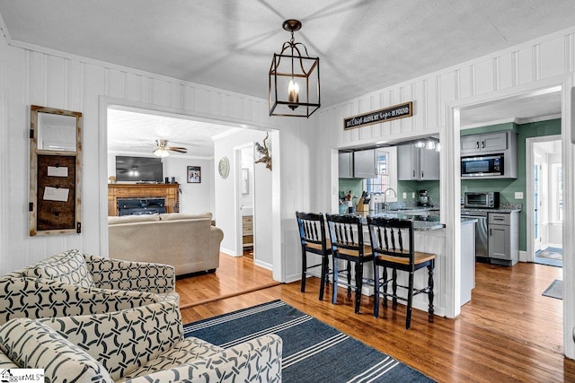 living room featuring crown molding, sink, ceiling fan with notable chandelier, and dark hardwood / wood-style flooring