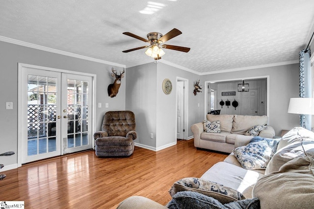 living room with crown molding, ceiling fan, a textured ceiling, french doors, and light wood-type flooring