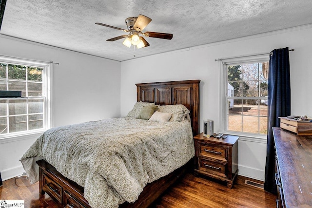 bedroom with ceiling fan, a textured ceiling, and dark hardwood / wood-style flooring