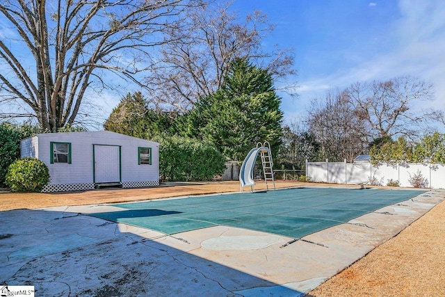 view of pool with a patio, a water slide, and an outdoor structure