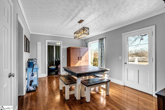 dining area featuring dark wood-type flooring, ornamental molding, and a textured ceiling