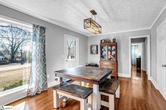 dining room featuring hardwood / wood-style flooring, ornamental molding, and a textured ceiling