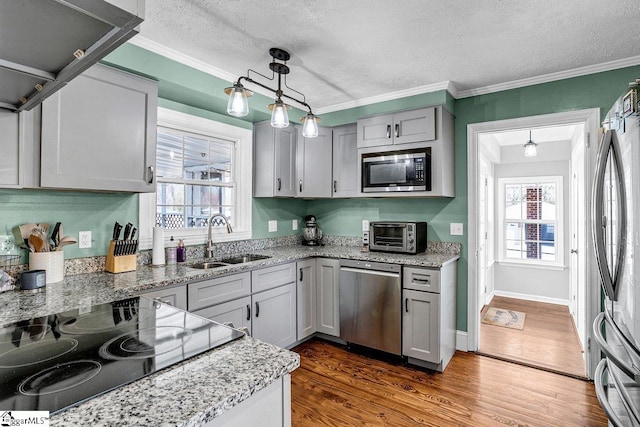 kitchen with pendant lighting, sink, appliances with stainless steel finishes, gray cabinetry, and wood-type flooring