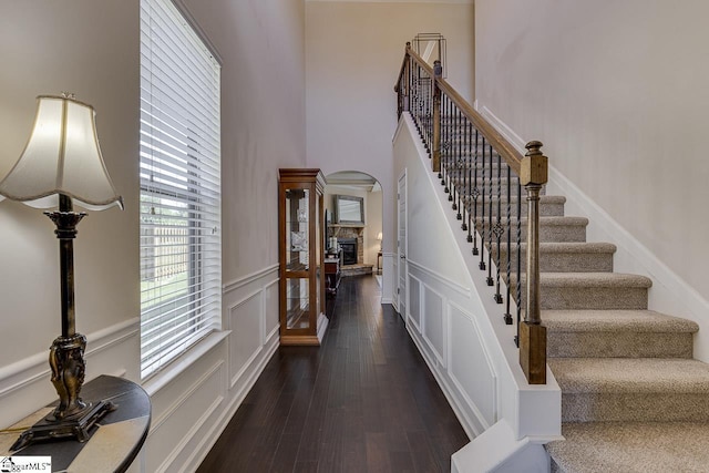 stairs featuring hardwood / wood-style floors, a towering ceiling, and a stone fireplace