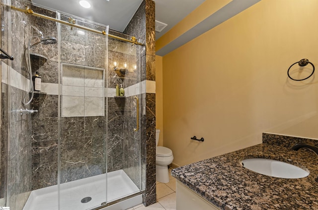 bathroom featuring tile patterned flooring, vanity, a shower with shower door, and toilet