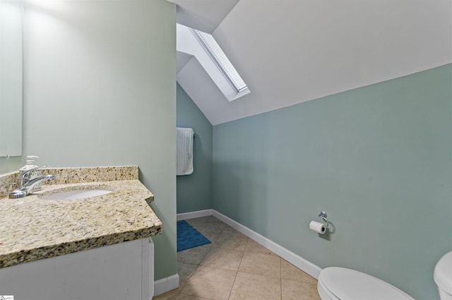 bathroom with vanity, tile patterned flooring, vaulted ceiling with skylight, and toilet