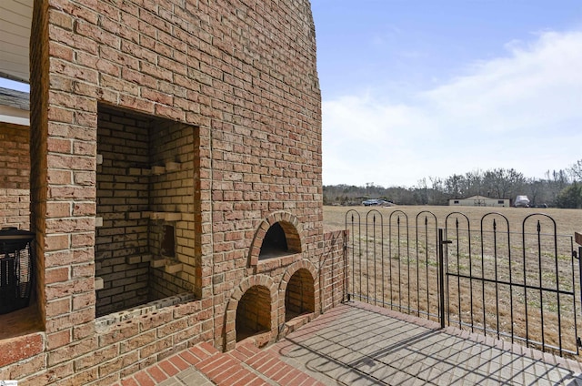 view of patio / terrace featuring an outdoor brick fireplace and a rural view