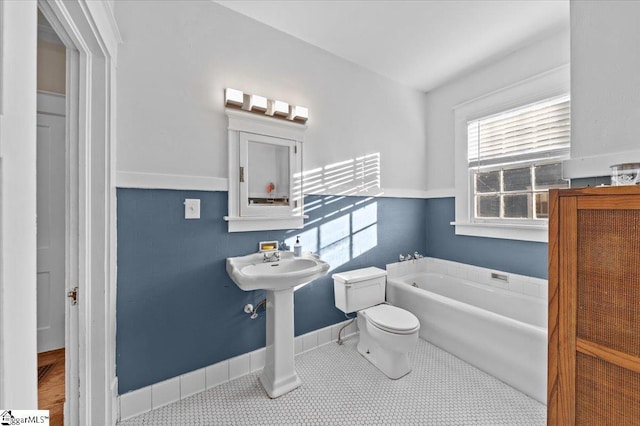 bathroom with tile patterned flooring, a bath, and toilet