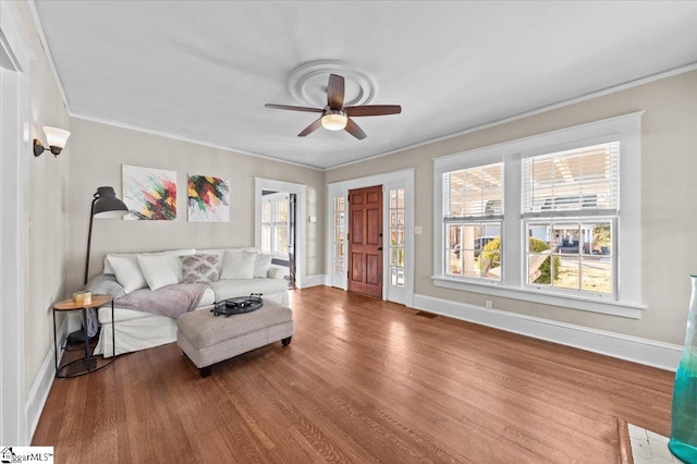 living room featuring hardwood / wood-style flooring, ceiling fan, and ornamental molding