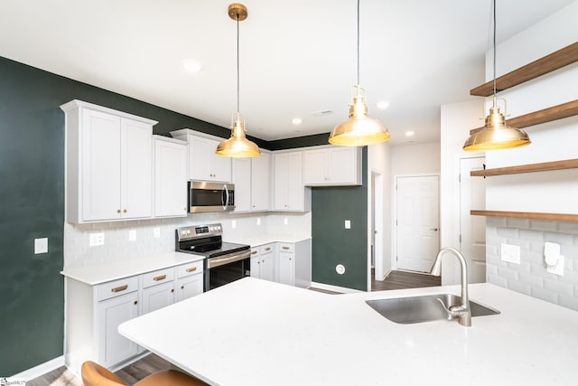 kitchen featuring white cabinetry, stainless steel appliances, sink, and hanging light fixtures