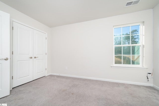 unfurnished bedroom featuring light carpet and a closet