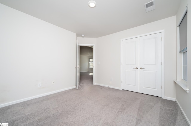 unfurnished bedroom featuring light colored carpet and a closet