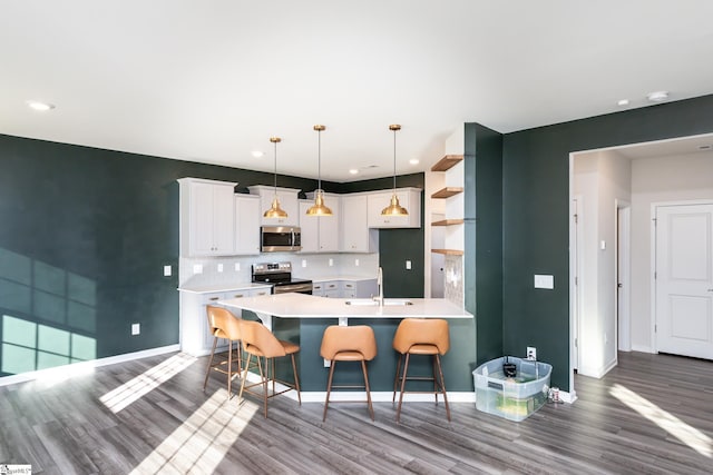 kitchen with decorative light fixtures, white cabinetry, sink, a breakfast bar area, and stainless steel appliances