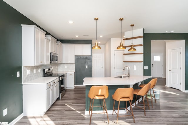 kitchen with appliances with stainless steel finishes, sink, white cabinets, and a kitchen breakfast bar