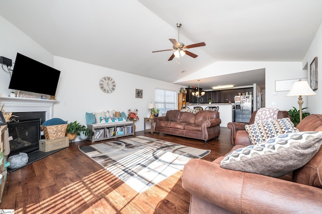 living room featuring ceiling fan with notable chandelier, wood-type flooring, and vaulted ceiling