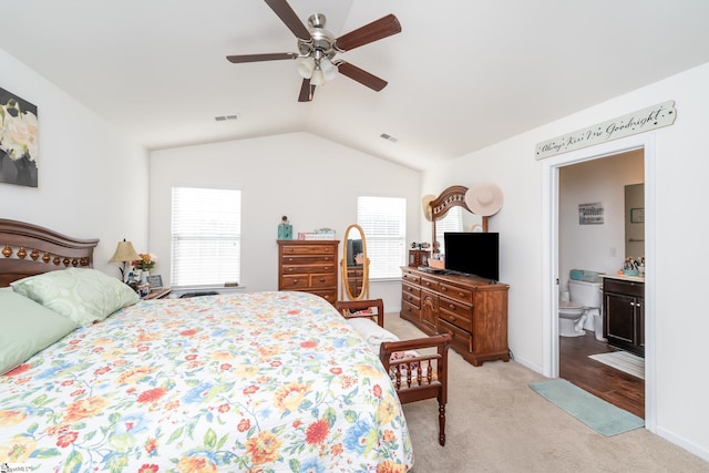 carpeted bedroom with vaulted ceiling, connected bathroom, and ceiling fan