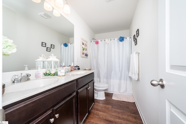 full bathroom with hardwood / wood-style flooring, vanity, shower / tub combo with curtain, and toilet