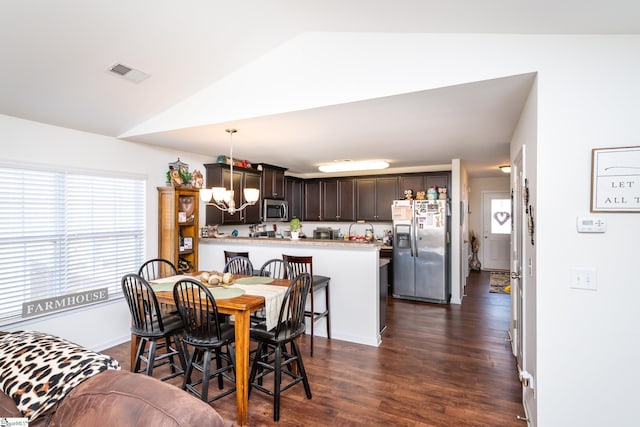 dining area with lofted ceiling, dark hardwood / wood-style floors, and a chandelier