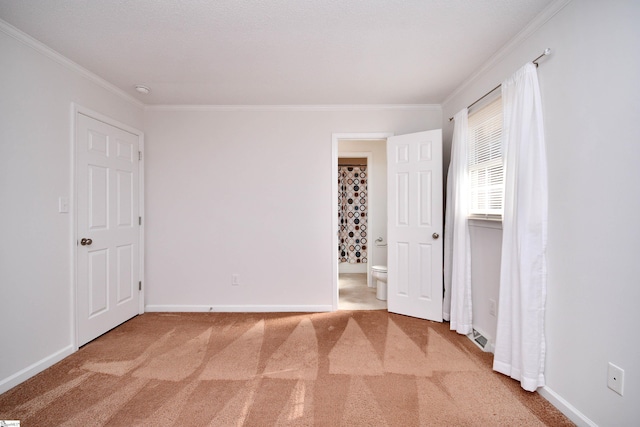 unfurnished bedroom featuring ornamental molding, ensuite bathroom, and carpet