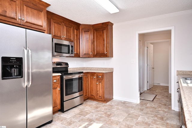 kitchen with a textured ceiling, light countertops, appliances with stainless steel finishes, and brown cabinetry