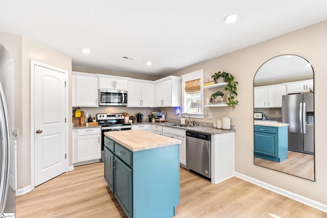 kitchen featuring a kitchen island, white cabinetry, appliances with stainless steel finishes, and blue cabinetry