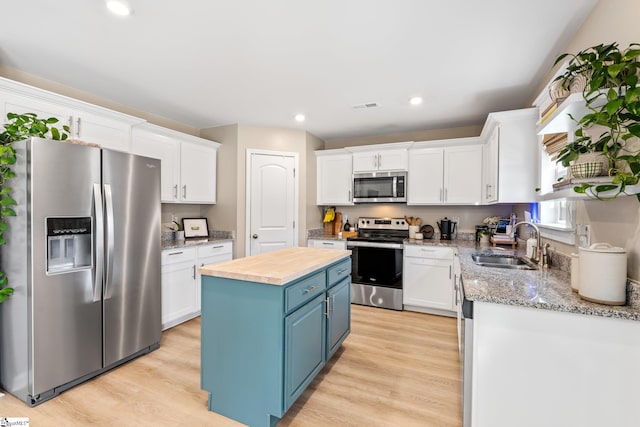 kitchen with a kitchen island, blue cabinets, sink, white cabinets, and stainless steel appliances