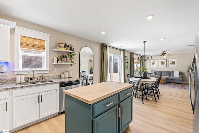 kitchen featuring butcher block countertops, sink, dishwasher, a kitchen island, and white cabinets