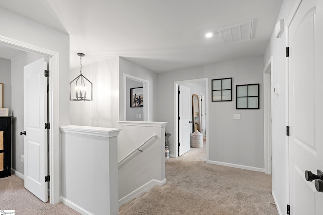 hallway featuring light colored carpet and a notable chandelier