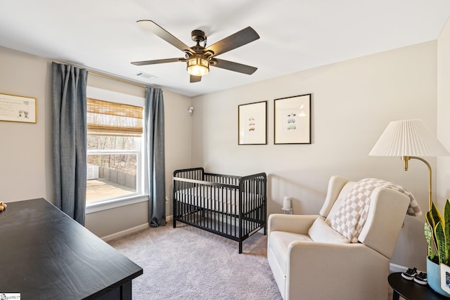 carpeted bedroom featuring a crib and ceiling fan