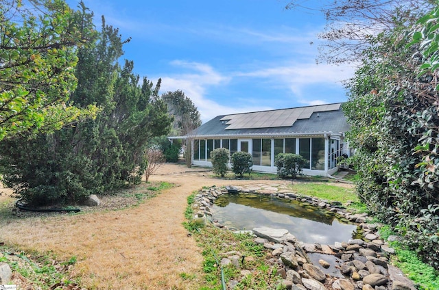 rear view of house featuring a sunroom and solar panels