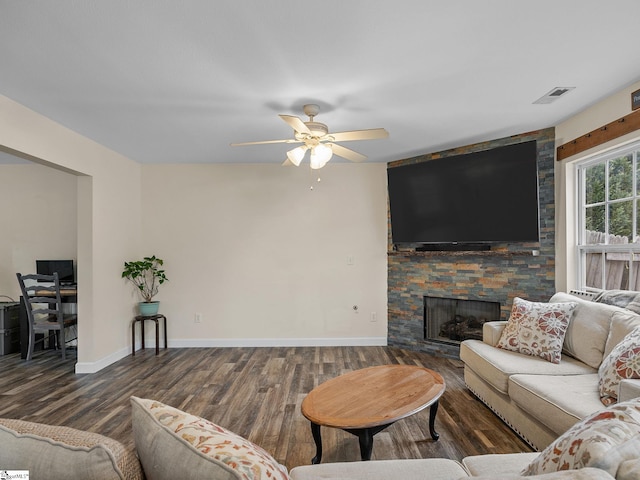 living room with ceiling fan, a stone fireplace, and dark hardwood / wood-style flooring