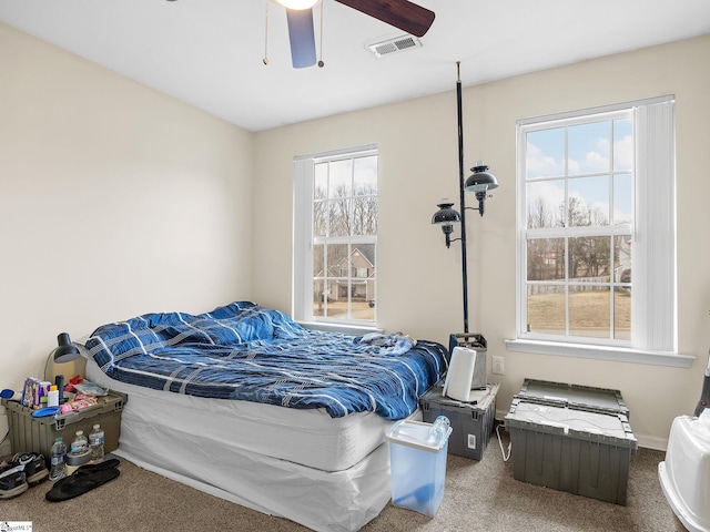 carpeted bedroom featuring multiple windows and ceiling fan