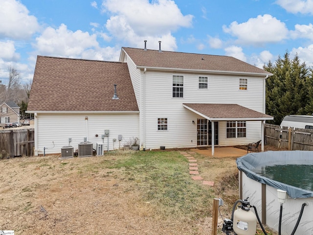 back of house featuring a patio, a covered pool, a lawn, and central air condition unit